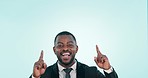 Business man, pointing up and excited in studio for choice, advertising and a blue background. Professional black male person with hand for mockup, solution or offer for idea or inspiration portrait