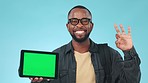 Face, green screen and black man with a tablet, perfect or connection on a blue studio background. Portrait, African person or model with tech, pointing or mockup space with ok sign, review or symbol