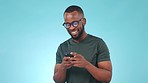 Smile, phone and black man in a studio typing a message on social media, mobile app or the internet. Happy, technology and young African male model scroll on cellphone isolated by blue background.