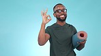 Yoga mat, ok sign and happy black man pointing at checklist, timeline or presentation in studio isolated on a blue background mockup space. Smile, portrait and okay hands of athlete or fitness coach