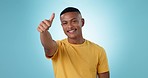 Face, smile and man with thumbs up, support and feedback with sign on a blue studio background. Portrait, person and model with hand gesture, review and emoji with vote, motivation and promotion