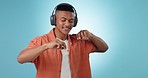 Headphones, energy and young man in a studio dancing and listening to music, playlist or album. Freedom, moving and male model from Mexico streaming a song on radio isolated by blue background.