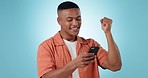 Studio phone, fist pump celebration and happy man reading news, giveaway announcement or competition victory. Cellphone notification, winner achievement or excited person celebrate on blue background
