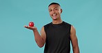 Apple, health and smile with face of man in studio for nutrition, diet and wellness. Fitness, food and detox with portrait of person and fruit on blue background for eating, organic and fiber snack