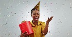 Birthday present, celebration and woman with confetti shower, prize and jump with happiness for win on white background. Gift, party and African giveaway winner, excited for bonus or reward in studio