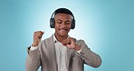 Dancing, headphones and young businessman in studio listening to music, radio or album for fun. Happy, moving and professional male person from Mexico streaming a song or playlist by blue background.