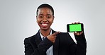 Phone, green screen and hand pointing by face of black woman in studio agreement on grey background. Smartphone, space and portrait of African lady model show news, guide or service, sign up or app