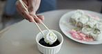 Closeup, hungry and hand with sushi at a restaurant at a table for fish, nutrition and eating. Sauce, fine dining and chopsticks with Asian cuisine or zoom on Japanese culture, seafood or plate