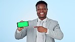 Green screen, phone and business man with hand pointing in studio for news, info or promo on blue background. Smartphone, display and portrait of African male entrepreneur show sign up, app or offer