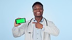 Green screen, phone and man doctor with hand pointing in studio for contact us, faq or help on blue background. Healthcare, presentation and portrait of African nurse with smartphone, app or sign up
