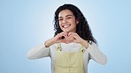 Heart, hands and face of woman in studio for kindness, happy icon and charity donation on blue background. Portrait, model and smile for love, hope and thank you for support, peace and emoji sign 