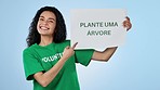 Volunteer, sign and woman plant trees in studio isolated on blue background. Portrait, pointing at poster for ecology and earth day, climate change and excited person protect environment or celebrate