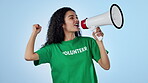 Woman, volunteer speaking and megaphone for protest, support and call to action or speech in studio. Face, person voice and volunteering in NGO tshirt with change or attention on a blue background