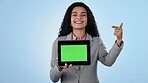 Green screen, smile and a business woman pointing at a tablet on a blue background in studio for marketing. Portrait, chromakey and a happy young employee showing space on a display for advertising