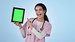 Tablet, green screen and woman nurse in a studio pointing to mockup space for advertising or marketing. Digital technology, chroma key and portrait of female healthcare worker by blue background.