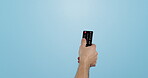 Hand, remote and changing channels on tv and isolated in studio by blue background. Close up of man, switching programs and surfing or streaming, series and movies on technology to relax in mockup