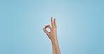 Hand, OK sign and emoji with feedback or review in studio, agreement and thank you with support on blue background. Person with vote, voice and opinion, mockup space with success and like or yes