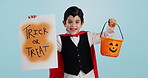 Halloween, poster and portrait of child with basket of sweets for candy isolated in studio blue background and happy. Holiday, laughing and kid in vampire costume for celebration in fantasy festival