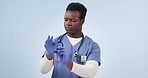 African man, doctor and gloves in studio for safety, surgery and stop bacteria for health by blue background. Medic, ppe and fitting for wellness, thinking or ready for job, emergency or hospital job