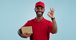 Delivery man, box and okay hands for success, product excellence and courier services in studio. Happy face of supply chain worker or african person for package or distribution on blue background