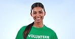 Volunteer woman, smile and studio for help, public care and social responsibility by blue background. Girl, community service and pride on face for activism, climate change or justice with job at NGO