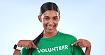 Volunteer woman, face and point in studio with t shirt, help and social responsibility by blue background. Girl, community service and pride for activism, climate change and charity with job at NGO