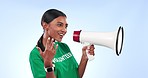 Volunteer woman, megaphone and speech in studio for help, recruitment or call to action by blue background. Girl, community service and rally for social responsibility, climate change or job at NGO