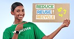 Volunteer woman, poster and recycling in studio with smile on face, eco sustainability or environment. Girl, cardboard sign or pointing for climate change, global warming or choice by blue background