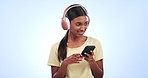 Woman, headphones and listening to music on mobile, audio streaming and podcast on a blue background. Young indian person with phone for radio, online subscription and agreement or yes in studio 