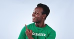 Happy, face and man volunteer with hand pointing in studio for faq, checklist or sign up info on blue background. Smile, portrait and African activist with how to guide, presentation or NGO platform