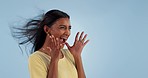 Happy, wind and woman in studio for celebration isolated on a blue background mockup space. Excited Indian model blowing hair for freedom, smile and celebrate success, winning goal and achievement