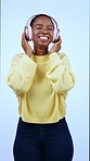 African woman, headphones and dancing in studio with smile, freedom and energy by blue background. Dancer girl, sound tech and audio streaming with laugh, thinking and listening with eyes closed