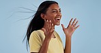 Excited, wind and woman in studio for celebration isolated on a blue background mockup space. Happy Indian model blowing hair for freedom, smile and celebrate success, winning goal and achievement