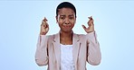 Portrait of nervous black woman in studio, fingers crossed in faith and opportunity for news. Waiting for results, stress in new job or deal, businesswoman with hope hand gesture on blue background.