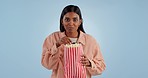 Face, excited and woman with popcorn, movies and entertainment on a blue studio background. Portrait, person and model with cinema snack, treats and streaming a film with suspense, eating and theatre