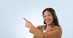Happy, pointing and face of woman in a studio with mockup for advertising, promotion or marketing. Smile, excited and portrait of young Asian female model with show hand gesture by white background.