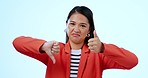 Thumbs up, face and woman in a studio with negative, approval or agreement hand gesture. Upset, portrait and young Asian female model with satisfaction or bad expression isolated by white background.