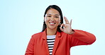 Face, business and woman with ok hand at studio isolated on a blue background. Portrait, okay sign and happy Asian person with emoji for success, excellence and perfect review, agreement or feedback