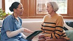 Tablet, discussion and nurse with senior woman in living room doing research for diagnosis or treatment. Conversation, healthcare and young female caregiver with digital technology to elderly patient