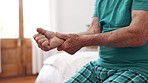 Closeup, hands and elderly man with wrist pain, injury and inflammation with bruise, home and broken. Zoom, pensioner and senior guy on a bed, fingers with ache and arthritis with sprain and strain