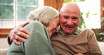 Senior couple, laugh and hug in home with love, care and discussion together in happy marriage in living room. Elderly man, old woman and embrace for funny conversation, joke and relax for retirement