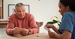 Woman, nurse and senior patient playing cards on table for fun game time or activity at old age home. Female person, medical or caregiver in poker, bonding or support for healthcare and entertainment