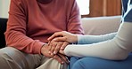 Nurse, holding hands and elderly care in support, trust or healthcare for understanding on living room sofa at home. Closeup of people touching in grief, loss or kindness for nursing or help at house