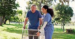 Senior man, walking and nurse in garden, park or woods with woman, support and help in retirement with conversation. Caregiver, helping and guide elderly person with walker, physio and healthcare