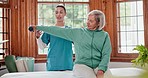 Senior woman with weights for workout with physiotherapist at physical therapy clinic for rehabilitation. Female healthcare worker helping elderly patient with arm exercise for mobility and strength.