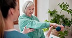 Elderly woman with weights for exercise with physiotherapist at physical therapy clinic for rehabilitation. Female healthcare worker helping senior patient with arm workout for mobility and strength.