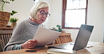 Senior, woman and documents with laptop for planning, investment or schedule for retirement in living room. Elderly, person or paperwork with technology, focus or research at table in lounge of home