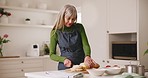 Mature woman, cooking and bread in kitchen or home with healthy food, recipe or nutrition in retirement. Cutting, knife or elderly person with gluten free diet or fresh organic loaf on table in house