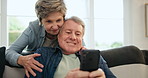 Senior couple, couch and smartphone with kiss, hug and smiling for embrace, living room and retired. Retirement, enjoying and bonding together for love, care and texting as pensioners, woman and man