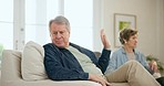 Senior couple, argument and conflict on sofa, anger and stress with hand to stop talking in home living room. Elderly man, woman and silence with fight, quite sign and frustrated face in retirement